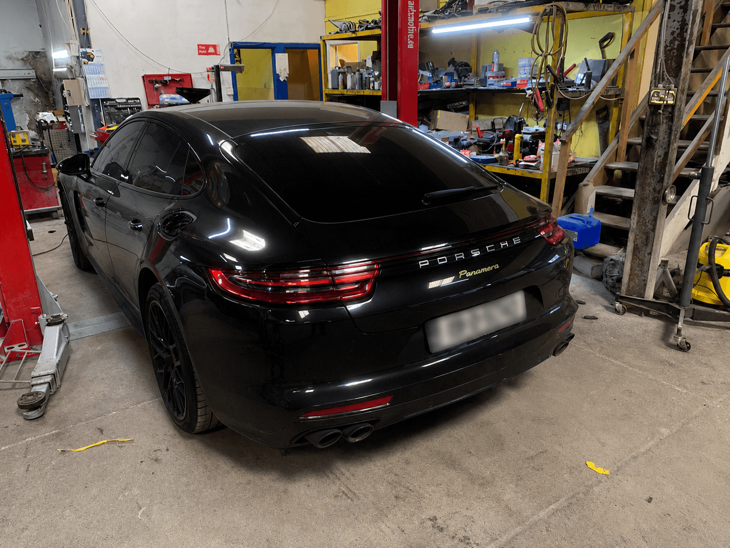 Black Porsche Panamera viewed from the rear inside the workshop